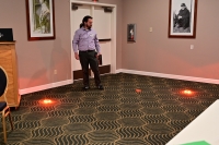 A man performs a demonstration with orange lights placed on the floor